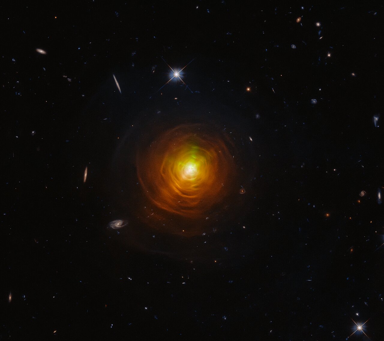 Hubble Space Telescope image of carbon star CW Leonis surrounded by concentric orange-red arcs of sooty dust